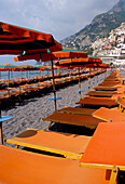 Beach with colourful orange sun loungers and umbrellas, Positano, Campania, Italy