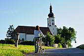 Frau schiebt Fahrrad, Wallfahrtskirche Mariä Himmelfahrt, Bad Kötzting, Bayerischer Wald, Niederbayern, Bayern, Deutschland