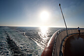 Kreuzfahrtschiff Queen Mary 2, Heck mit Kielwasser, Fahnenmast, Reling und Passagier, Transatlantik, Nordatlantik, Atlantik