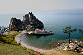 Boat in bay by Shaman Rock at Cape Burchon on Olchon Island, Lake Baikal, Russian Federation