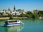 Riverboat on Rio Guadalquivir and view of city, Seville, Andalucia, Spain