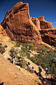 Group of hikers and red rock formation scenery, Arches National Park, Utah, USA