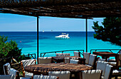 View from cafe terrace of bay with boats, Liscia di Vacca, Sardinia, Italy