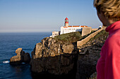 Junge Frau schaut zur Leuchtturm, Kap Cabo de Sao Vicente, Atlantischer Ozean, MR, Sagres, Algarve, Portugal