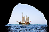 View from a cave towards sailing boat Santa Bernada, now taking tourists along the steep coast of the Algarve, Portimao,  Algarve, Portugal