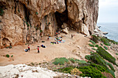 People in front of a cave on shore, Biddiriscottai, Cala Conone, Sardinia, Italy, Europe