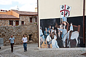 Touristen betrachten Wandmalerei an einem Haus, Orgosolo, Sardinien, Italien, Europa