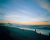 Family strolling along the beach at sunset, Okuru Beach, West coast, South Island, New Zealand