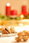 Nussknacker und Walnüsse mit Adventskranz mit einer brennenden Kerze im Hintergrund
