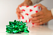 Green bow with person packing gift in background