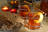 Zwei Teegläser mit Orangenschale und Zimtstange dekoriert und Schale mit Weihnachtsgebäck