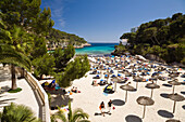 Menschen am Strand mit Sonnenschirmen in der Bucht Cala Santanyi, Mallorca, Balearen, Mittelmeer, Spanien, Europa