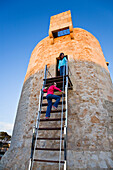 Two girls on the ancient watchtower in the evening light, Cala Santanyi, Mallorca, Balearic Islands, Mediterranean Sea, Spain, Europe