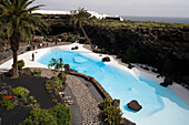 Swimming pool with palm trees near a volcanic cave, Jameos del Agua, hollow lava tunnel, architect Cesar Manrique, UNESCO Biosphere Reserve, Lanzarote, Canary Islands, Spain, Europe