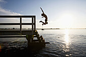 Boys leaping off a pier in Denmark