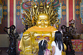 Zwei Mädchen vor einer Buddhafigur im Wat Phanang Choeng, Ayutthaya, Provinz Ayutthaya, Thailand, Asien