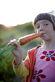 Girl (6-7 years) eating a carrot, Lower Saxony, Germany
