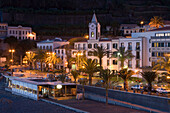 Strandpromenade mit Kirchturm und Enotel Baia do Sol Hotel im Dämmerlicht, Ponta do Sol, Madeira, Portugal