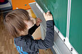 Schoolboy writing on blackboard, Hambug, Germany