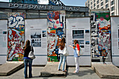 Young Women, Tourists In Front Of Fragments Of The Berlin Wall, Potsdamer Platz, Berlin, Germany