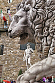 Statue Of The Lion In The Loggia Dei Lanzi In Front Of The Of Statue Of David By Michelangelo In Front Of The Palazzo Vecchio, Piazza Della Signoria, Florence, Tuscany, Italy