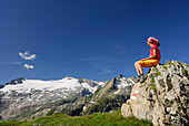 Frau sitzt auf Felsblock und blickt auf Basodinogletscher, Tessiner Alpen, Tessin, Schweiz