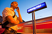 Mann telefoniert mit einem Handy auf einem Bahnsteig, Leipzig, Sachsen, Deutschland