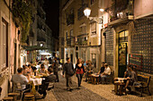 Nachtaufnahme von Menschen vor Alfaia Wein Bar in der Altstadt, Lissabon, Portugal, Europa