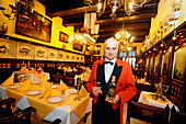 Waiter at the restaurant Pod Lososiem holding a bottle of gold water, Gdansk, Poland, Europe