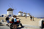 Menschen und Windmühlen im Venetia Viertel unter blauem Himmel, Insel Mykonos, Kykladen, Griechenland, Europa