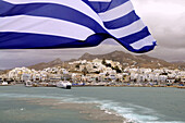 Ensign and ferryboat in front of the town of Naxos, island of Naxos, the Cyclades, Greece, Europe
