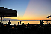 Menschen an der Promenade bei Sonnenuntergang, Parikia, Insel Paros, Kykladen, Griechenland, Europa