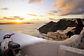 Frau auf einer Mauer betrachtet den Sonnenuntergang, Firostefani an der Caldera, Santorin, Kykladen, Griechenland, Europa