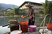 Chinesische Bäuerin schöpft Wasser aus kleinem Fluss, Dorf der Hakka, Hongkeng, Longyan, Fujian, China, Asien