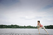 Junge Frau beim Stretching auf einem Steg am Starnberger See, Bayern, Deutschland