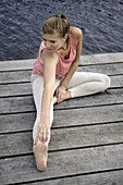 Young woman stretching on a jetty at lake Starnberg, Bavaria, Germany