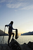 Woman holding climbing rope, lake Garda in background, Nago-Torbole, Trentino-Alto Adige/South Tyrol, Italy