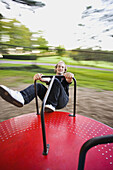 Young man on a spinning playground ride.