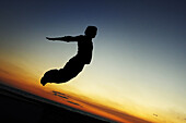 Parcours: A boy practicing jumps to the dusk in the beach