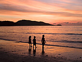 three children silhouetted on the beach at sunset in Phuket Thailand