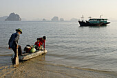 Vietnamese family sailing on a porexpan raft from the beach of Bai Dai to their boat-house. Bai Tu Long,  Vietnam.