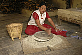 A woman grinding grain with a hand mill  Annapurna Circuit,  Nepal