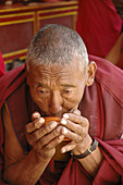 Older monk sipping tea Lama Yuru,  Ladakh,  India