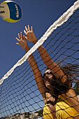 Young woman playing volleyball, wearing a yellow bikini, Mallorca, Balearic Islands, Spain