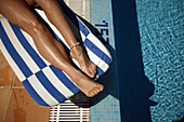 Womans' legs on a sunlounger by the pool