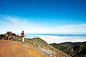 Hiker on a mountain looking at cloud cover, Roque de los Muchachos, Caldera de Taburiente, La Palma, Canary Islands, Spain, Europe