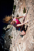 Eine junge Frau klettert an den Klippen der Bucht von Zurrieq, Malta, Europa