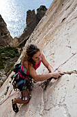 A young woman, a climber, a sportclimber, freeclimber, climbing at Ix-Xaqqa rock face, Malta, She protects with nuts and wires, Europe