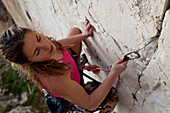 Eine junge Frau, eine Sportkletterin, Freeclimberin, klettert an der Felswand von Ix-Xaqqa, Malta, Europa
