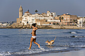 Young girl and her dog on the beach, Sitges, Catalonia, Spain, Europe